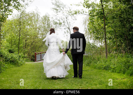 Una sposa in bianco di un abito da sposa a piedi con il suo sposo nella natura Foto Stock