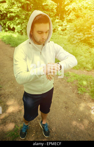 Guida sul sentiero di montagna guardando sport smart watch Foto Stock