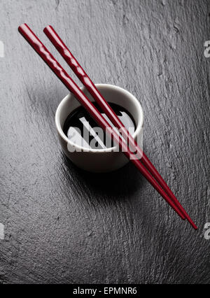 I sushi giapponesi Le bacchette su salsa di soia ciotola nero su sfondo di pietra Foto Stock