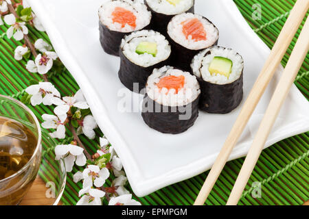 Maki Sushi set, il tè verde e il ramo sakura sulla tabella di bambù Foto Stock