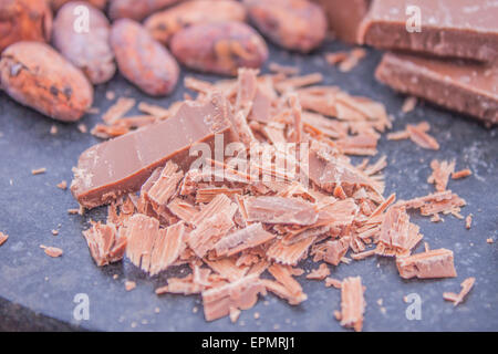 Un mucchio di cioccolato grattugiato, nella parte anteriore delle fave di cacao e di cioccolato al latte Foto Stock