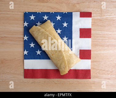 Vista dall'alto di un cotto in forno a microonde chimichanga su una bandiera americana motif igienico in cima a una tavola di legno alto. Foto Stock