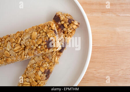 Chiudere la vista dei due chip di cioccolato granola bar su una piastra in cima a una tavola di legno alto. Foto Stock