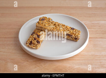 Vista laterale di due chip di cioccolato granola bar su una piastra in cima a una tavola di legno alto. Foto Stock