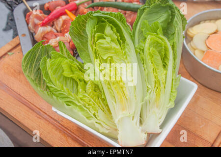 Insalata Romaine la metà, in attesa di essere grigliate. Nei pressi di spiedini di carne e verdure Foto Stock