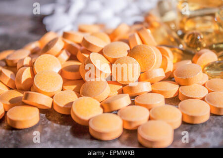 Orange b-vitamina pillole su una lastra di pietra, bianco altri supplementi Foto Stock