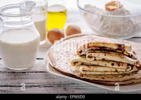 Close-up di crepes Stack e gli ingredienti per cucinare su una tavola di legno. Stile rustico. Messa a fuoco selezionata. Foto Stock