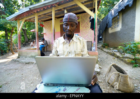 L'uomo, 34 anni, seduto di fronte a casa sua con un laptop, Riviere Froide, Haiti Foto Stock