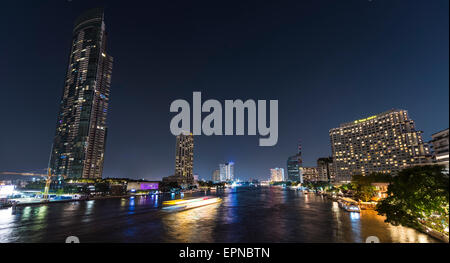 Skyline e barca sul fiume Mae Nam Chao Phraya, di notte, Bangkok, Thailandia Foto Stock