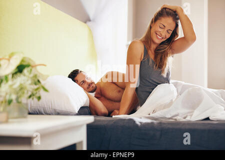 Felice coppia giovane svegliarsi al mattino sul letto. Giovane uomo e donna sorridente, rilassati nella mattina. Foto Stock