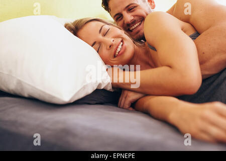 Felice coppia giovane abbracciando sdraiati accanto a ogni altro sul letto. Caucasian Coppia sorridente nel letto insieme. Paio di risveglio. Foto Stock