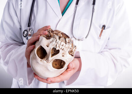 Medico tenendo un cranio nelle sue mani. Ella mostra il cranio in avanti in una situazione di insegnamento o quando ella spiega il suo paziente cosa t Foto Stock