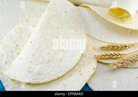 Tortilla di fresco e un bastone di grano su una tovaglia blu Foto Stock