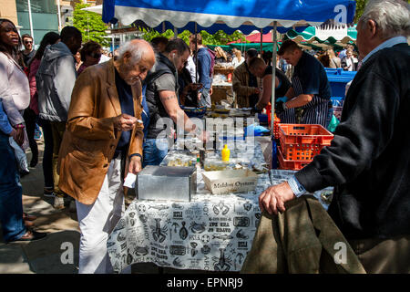 Uomini di mangiare le ostriche al sabato mercato alimentare a Duke of York's Square , King's Road, Londra, Inghilterra Foto Stock