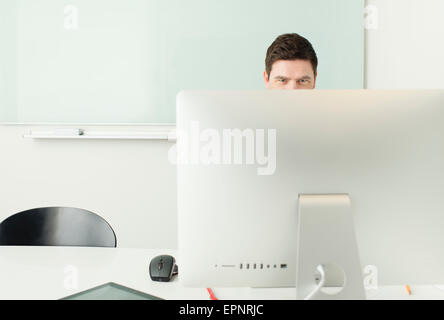 Imprenditore seduto da scrivania, lavorando con computer in ufficio. Foto Stock