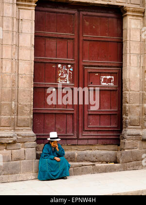 Tipico Quechua donna seduta davanti a una porta - Cuzco, Perù Foto Stock