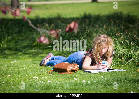 Regno Unito, Londra : Una ragazza si stende sul prato con un libro durante il tempo caldo in St James Park a Londra oggi. Foto Stock