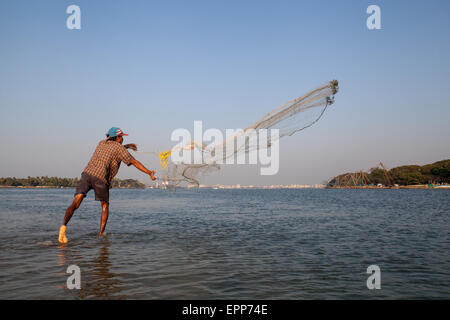 Pescatore getta la sua rete in mare a Fort Cochin in Kerala Foto Stock