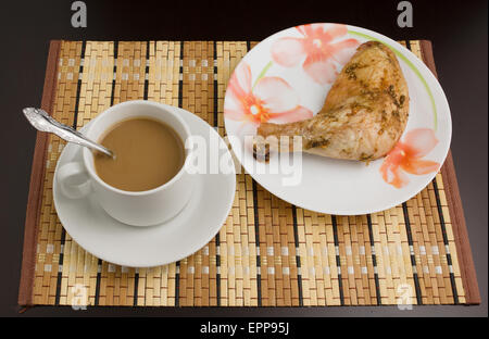 Caffè del mattino in una tazza bianca e prosciutto di pollo su una piastra supporto su una tabella Foto Stock