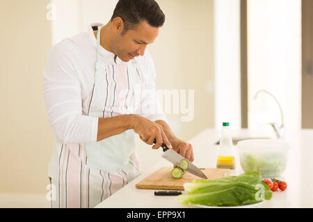 Metà uomo età tritare verdure in cucina Foto Stock