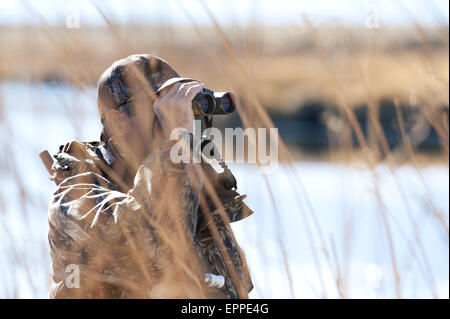 Un cacciatore utilizza un binocolo in Nevada. Foto Stock