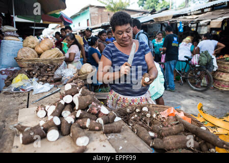 GRANADA, Nicaragua — Un venditore presso il Mercado Municipal prepara la yuca fresca in vendita. La preparazione quotidiana di prodotti come la yuca, un ingrediente chiave in piatti tradizionali come il vigorone, continua le antiche tradizioni del mercato. I venditori di mercato mantengono ruoli essenziali nel sistema di distribuzione alimentare di Granada. Foto Stock