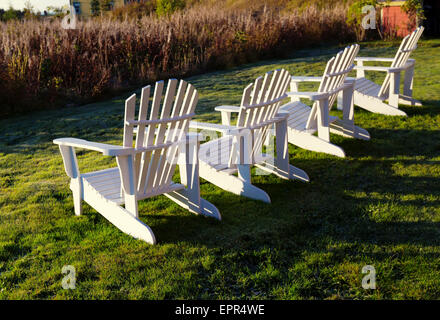 White Adirondack sedie in fila con la luce della sera. Foto Stock