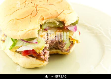 Un morso cheeseburger con tutti i condimenti isolato su bianco Foto Stock
