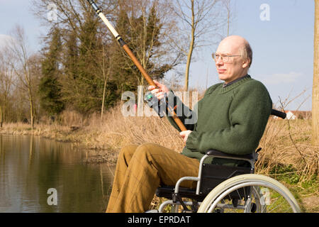 Uomo in sedia a rotelle la pesca Foto Stock