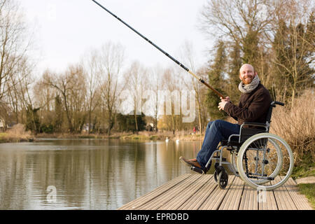 Giovane uomo su una sedia a rotelle la pesca Foto Stock