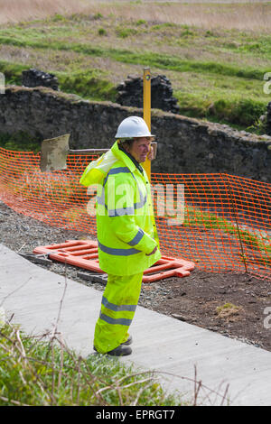 Operatore che trasporta pala e livella a bolla d'aria - operai che gettano un nuovo percorso a Porthgain, Pembrokeshire Coast National Park, Galles, Regno Unito a maggio Foto Stock