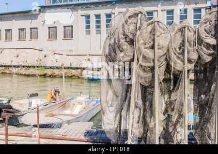 Le reti da pesca in banchina, in background le barche da pesca Foto Stock