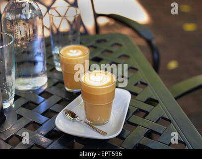 Due cortado caffè in bicchieri in outdoor, patio con tavolo di acqua in bottiglia e vetro, Canada Foto Stock