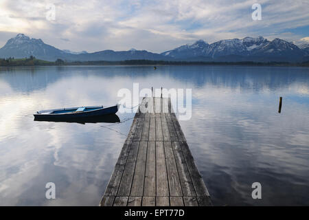 Pontile in legno con canotto, Hopfen am See, Lago Hopfensee, Baviera, Germania Foto Stock