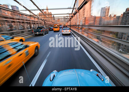 A guidare oltre il Ponte di Brooklyn in una VW Beetle verso Manhattan, New York, New York, Stati Uniti d'America.