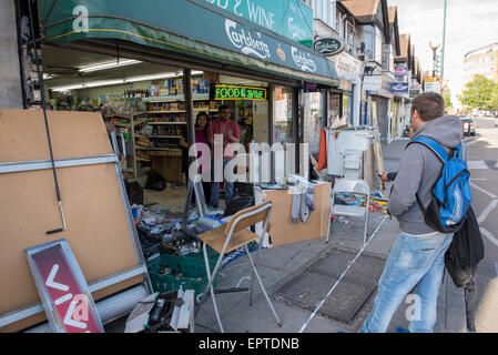 Londra, Regno Unito. Il 21 maggio 2015. Proprietari iniziare la pulizia dopo l'auto va in crash attraverso il negozio di fronte a Wembley. Londra, Regno Unito. Credito: Peter Manning/Alamy Live News Foto Stock