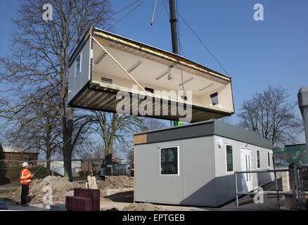 Durante l'installazione di un nuovo edificio a 2 sezioni, una sezione di un'aula modulare è appesa a una gru. Foto Stock