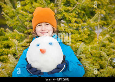 Ragazzo in blu giacca invernale azienda pupazzo di neve la testa Foto Stock