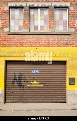 Brown porta di garage in un muro di mattoni con vernice gialla Foto Stock