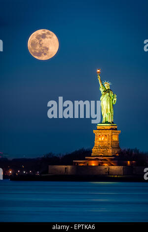 La Statua della Libertà e un crescente supermoon nella città di New York Foto Stock