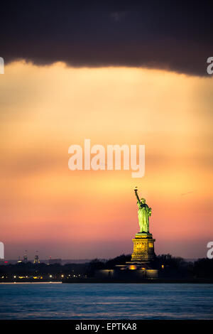 Statua della Libertà sotto una drammatica la luce del tramonto visto da Brooklyn, New York Foto Stock