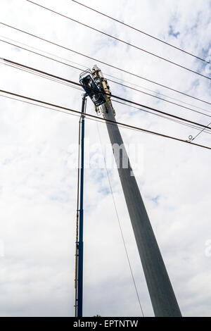 Due uomini al lavoro da sollevare la benna su un cellulare o un telefono cellulare tower in Modesto California Foto Stock