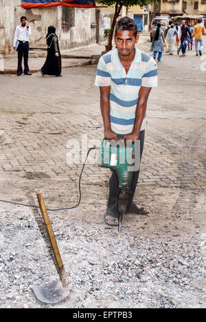 Mumbai India,Dharavi,Shahu Nagar Road,slum,uomo uomo maschio,martello elettrico,lavoro su strada,riparazione,lavoro,lavoro,India150228037 Foto Stock