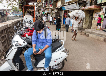 Mumbai India,Dharavi,Shahu Nagar Road,teen teen teenager ragazzi maschi ragazzi bambini bambini cercando,cercando di leggere messaggi di testo, sma Foto Stock