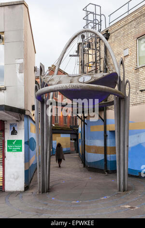 Una donna che cammina da sola passata e vuota saliti fino ai negozi in una corsa verso il basso area di una città. Il maggiordomo del passaggio, Walsall, West Midlands, England, Regno Unito Foto Stock