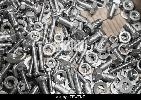 Shining bulloni e dadi in una scatola di cartone, dello sfondo della foto con il fuoco selettivo Foto Stock