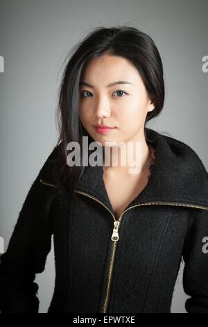 Attraente ragazza asiatica nel suo ventenne isolato su un sfondo plein girato in uno studio Foto Stock