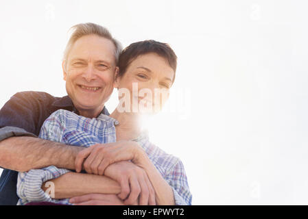 Ritratto di sorridente coppia senior abbracciando nella luce solare Foto Stock