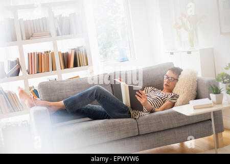 Senior donna leggendo un libro sul divano Foto Stock