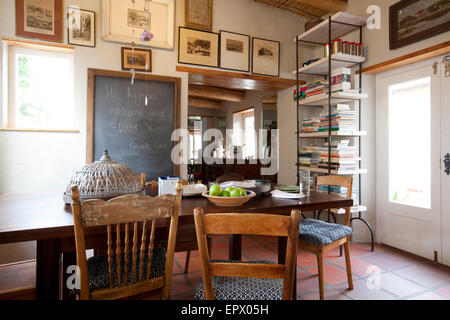 Cucina tavolo da pranzo con blackboard messaggio, sedie di antiquariato e opere d'arte in South African home Foto Stock